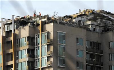 　　昨日，身穿橘黃色馬甲的工作人員在人濟(jì)山莊樓頂拆除違章建筑。新京報(bào)記者 吳江 攝