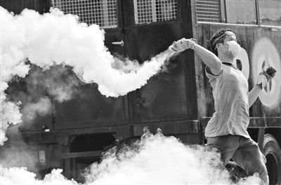 12月2日，泰國曼谷，一名反政府示威者在總理府附近向負(fù)責(zé)執(zhí)勤的警察投擲催淚彈。英拉請(qǐng)求示威者不要再試圖占領(lǐng)政府工作部門，不要逼迫政府工作人員選邊站。