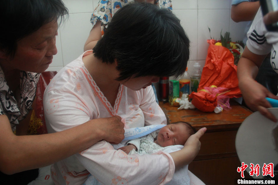 圖為久別重逢，獲救嬰兒母親悉心撫摸愛子。張一辰 攝