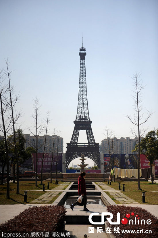 　2014年3月21日，杭州天都城，農(nóng)民在山寨埃菲爾鐵塔下耕作。圖片來源：東方IC