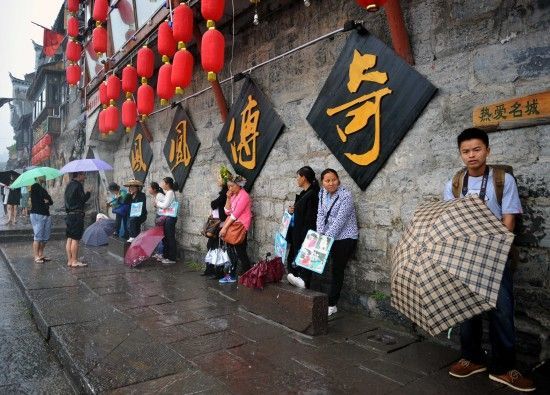 　4月29日上午11時(shí)20分，一些游客和古城當(dāng)?shù)氐木用穸阍谝粋€(gè)酒吧的屋檐下避雨。這些當(dāng)?shù)鼐用褚詾橛慰团恼罩\生，一場(chǎng)降雨讓他們的生意更加清淡。