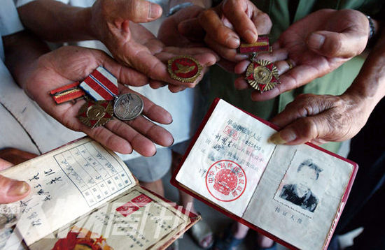 幾位志愿軍老兵展示自己的立功證、傷殘軍人證與勛章