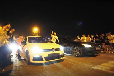 8月24日晚，東壩中街飆車現(xiàn)場，兩輛車并排等待出發(fā)指令，旁邊許多愛好者前來觀看比賽。新京報記者