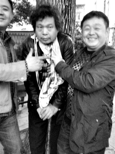 兩名接訪人員與患有癌癥的訪民段新德合影時，面帶笑容擺出勝利的手勢。