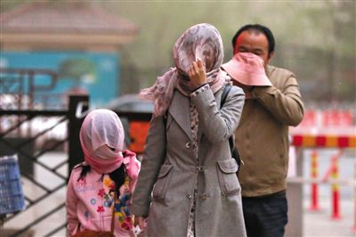 昨日下午，朝陽區(qū)豆各莊，行人將紗巾裹在頭上防沙塵。