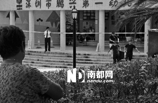 →7月19日，鵬興花園第一幼兒園門前，民警在現(xiàn)場進行完勘查取證后，園長和保安的尸體被運走。南都記者 徐文閣 攝