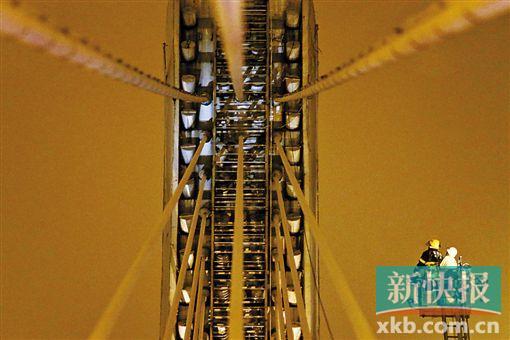 截至今日零時(shí)，男子仍未有下橋舉動(dòng)。圖為公安和消防人員乘消防云梯在高空上和男子交談。