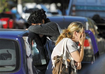 27日，遇難者親友在火災(zāi)現(xiàn)場旁哭泣。