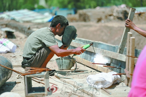 　正午陽光下，工地上的焊接工人還在認真工作。