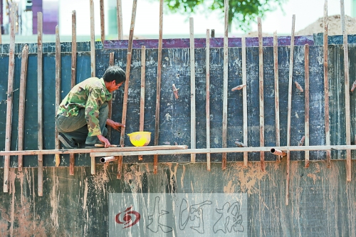 　　烈日下，狹窄的架子上，工人正用錘子固定樁基。