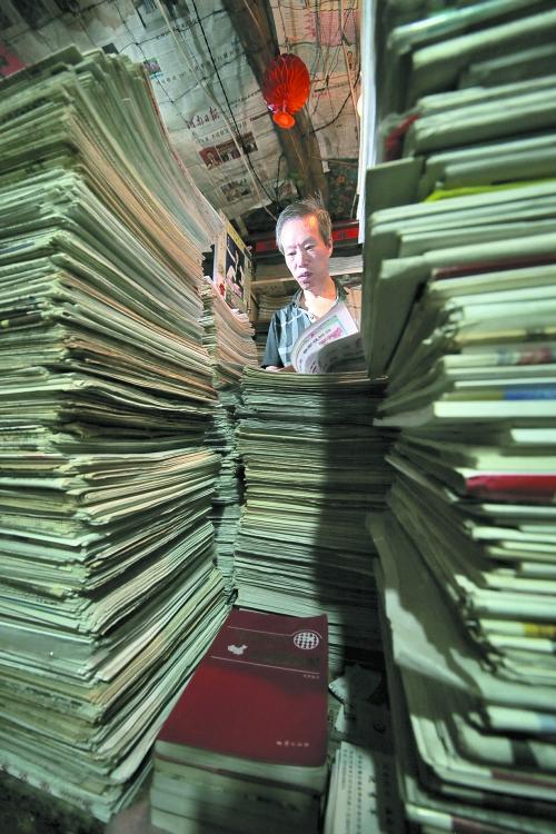 王曉民坐在寫字桌前，被報(bào)紙淹沒。