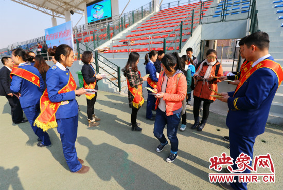 活動現(xiàn)場工作人員給同學們發(fā)放宣傳冊、環(huán)保袋。