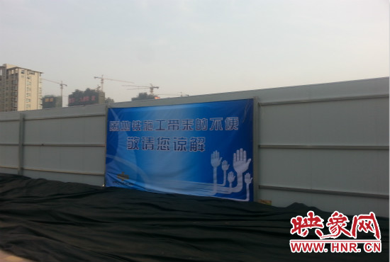 道路南側(cè)圍起了白色的圍擋，墻上標(biāo)示著“因地鐵施工帶來(lái)的不便敬請(qǐng)您諒解”的提示牌。