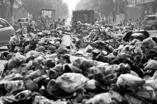 垃圾堆滿整個(gè)路口，環(huán)衛(wèi)工人們正在清理