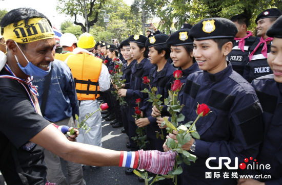 2013年12月03日,曼谷總理府與曼谷警署允許反政府示威民眾進入,雙方進入暫時“停戰(zhàn)”狀態(tài)迎接泰王生日。曼谷警察總署,女警們手持鮮花送給反政府示威民眾。圖片來源:Manish Swarup/東方IC