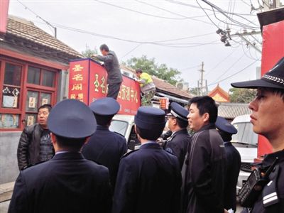 昨日下午,東城區(qū)工商、城管、公安等部門,對雍和宮附近的預(yù)測中心進(jìn)行清理整頓,站在車頂?shù)膬擅と苏鸪患摇邦A(yù)測中心”的招牌。因雍和宮、白云觀等文化景點外聚集大量算命先生,被媒體稱為“算命一條街”。本版攝影/新京報記者 李寧 攝