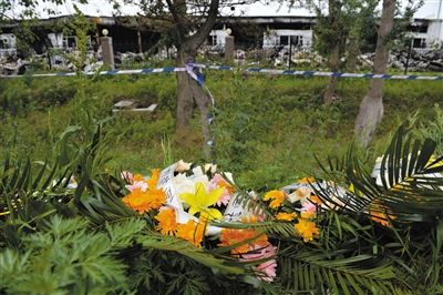 昨日，吉林省德惠市吉林寶源豐禽業(yè)有限公司燃燒事故現(xiàn)場警戒線外，遇難者家屬在路邊擺放了花圈祭奠逝去的親人。吳江 攝