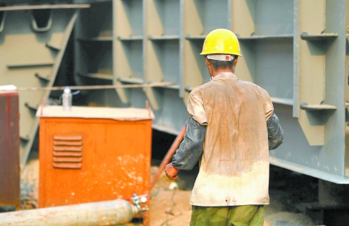 工地上，一建筑工人的衣服被汗水浸透。