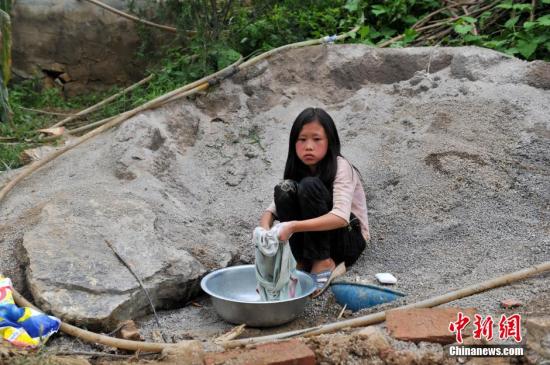 8月9日，云南巧家紅石巖村，10歲的劉鑫蕊在洗自己的衣服