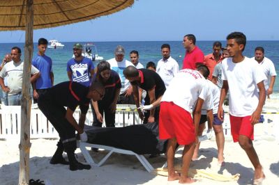 6月26日，在突尼斯蘇塞，救生員和醫(yī)務(wù)人員在發(fā)生襲擊事件的海灘運(yùn)送一名死者的遺體。新華社發(fā)