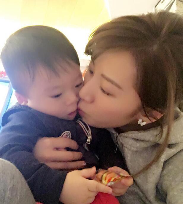 照片中李念狂吻兒子，小寶貝自顧自地玩著。