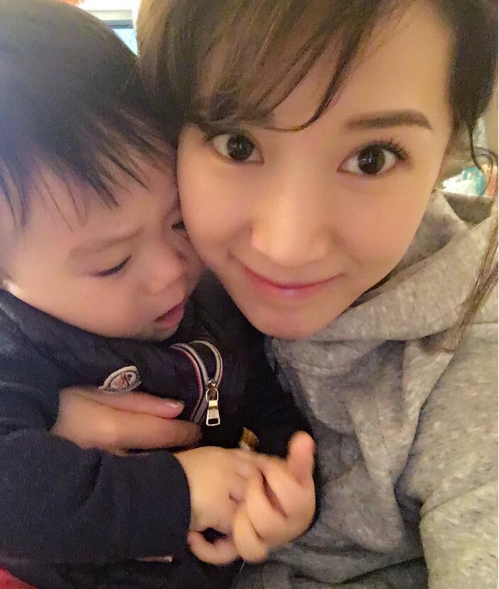 照片中李念狂吻兒子，小寶貝自顧自地玩著。