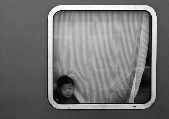 一個(gè)孩子把頭伸向窗外，他想再看送別的親人一眼