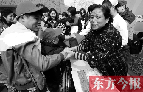 昨日，鄭大四附院的大樓前，“面人鄭”鄭玉芬（右）向前來捐款的殘疾人表示感謝