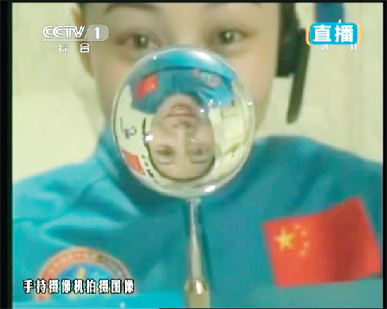 王亞平的倒影出現(xiàn)在水球中。新華社發(fā)（視頻截圖）