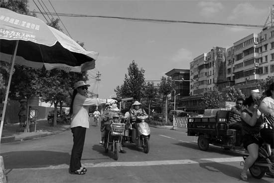 昨日，開(kāi)封市區(qū)一名協(xié)管員在指揮群眾過(guò)馬路