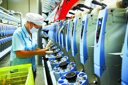 7月3日，在鄧州市永泰棉紡有限公司電腦控制全自動紡紗車間，紡織工人正在生產棉紗。