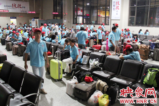 大學(xué)生志愿者在火車站候車室內(nèi)整裝待發(fā)。