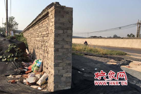 一墻之隔，一邊是道路，一邊是垃圾和荒草，市民質(zhì)疑其為遮羞墻。