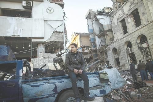 埃及曼蘇拉市警察局24日遭汽車炸彈襲擊，被疑是穆兄會的報復(fù)。圖為一名男子在被炸毀的警察局前。