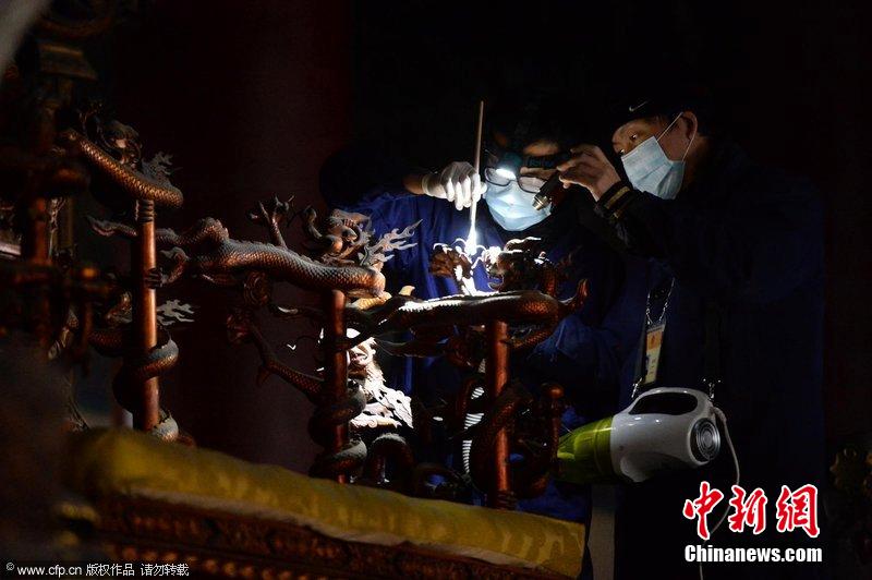 圖為工作人員使用軟毛刷和吸塵器對太和殿的金漆雕龍寶座除塵。