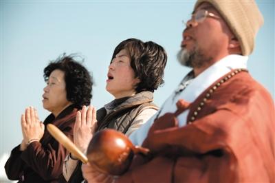 23日，一名僧侶引領人們?yōu)樗勒咂矶\。