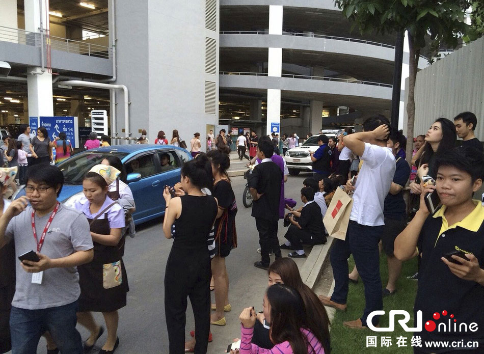 當(dāng)?shù)貢r(shí)間2014年5月5日，泰國(guó)清萊，工人們站在一棟大樓外避難。