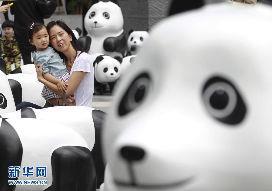 6月2日，一位家長帶著孩子在上海街頭和大熊貓模型合影。