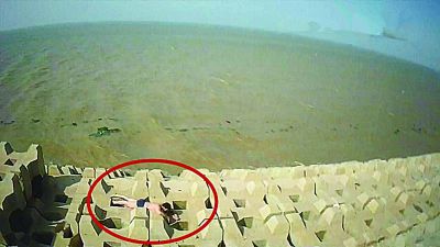 孫正龍游上岸，趴在海邊精疲力盡。