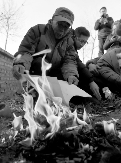 李三仁在兒子墳前焚燒再審無罪判決文書的復印件。新華社發(fā)