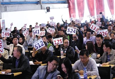 競(jìng)拍者正在練習(xí)舉牌動(dòng)作，以便拍賣時(shí)讓工作人員看清號(hào)牌。