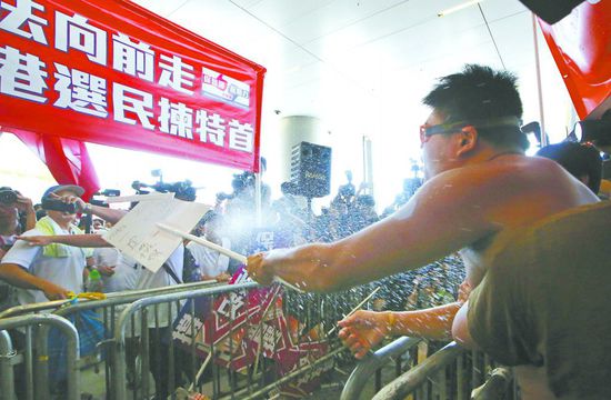 17日，在香港立法會(huì)外，一名反對(duì)政改的男子向支持派人群投擲標(biāo)牌。