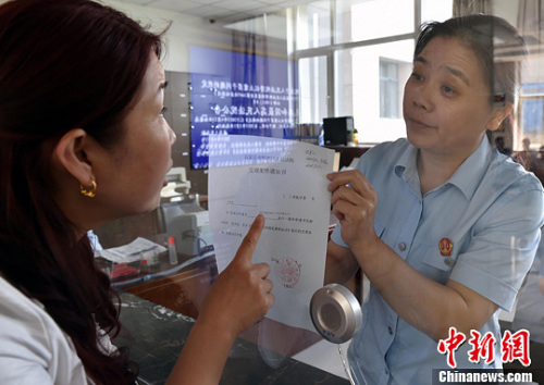 資料圖：2015年5月4日，河北石家莊市橋西區(qū)人民法院立案庭庭長齊燕正在為立案人辦理相關(guān)手續(xù)，完成整個(gè)過程只用了5分鐘。當(dāng)日是立案登記制改革首個(gè)工作日，該院共立案36件，立案率達(dá)到90%。中新社發(fā) 翟羽佳 攝