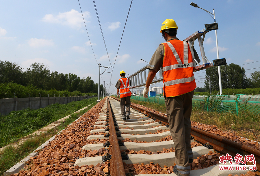 滾燙的鐵軌上，兩個扛著梯子的檢修員走向第四個檢修點