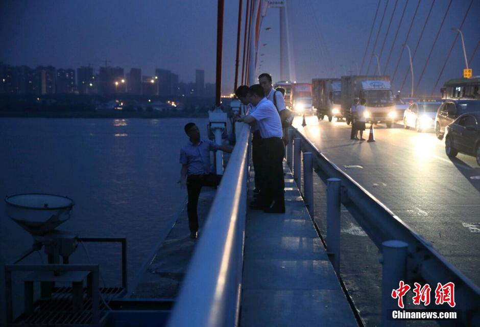 圖為武漢警方談判專家正在與翻爬至大橋外側(cè)護(hù)欄的劫持者談判。