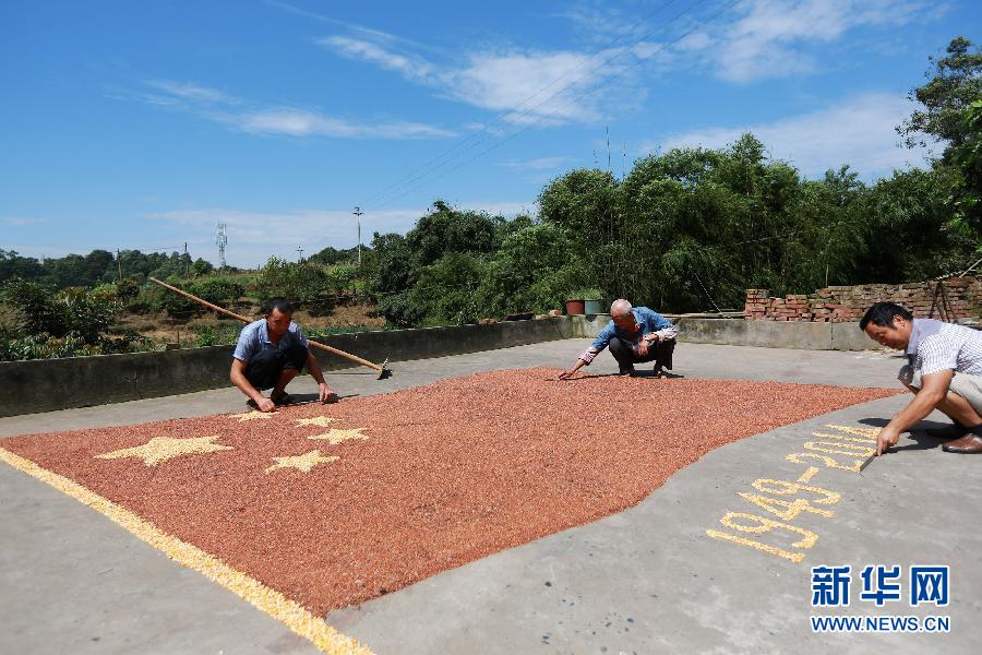 村民馬玉明（左一）用豐收的高粱和玉米在院壩里擺國(guó)旗為祖國(guó)慶生。