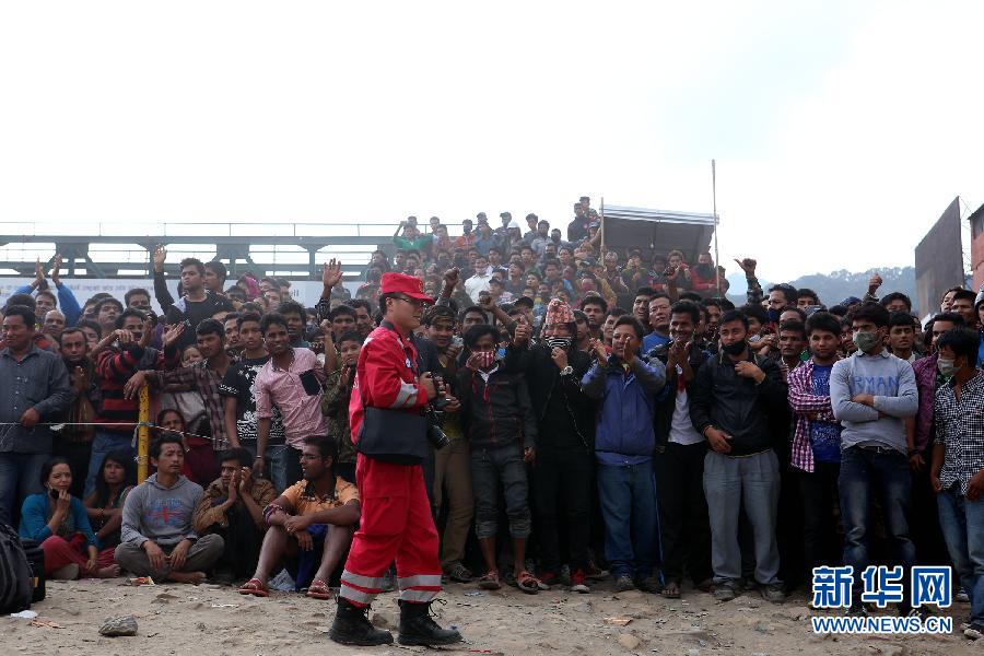 圍觀的尼泊爾民眾在中國國際救援隊(duì)成功搜救出幸存者后向搜救隊(duì)員歡呼致意。