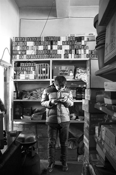 1月21日，周瑋在自家的超市里玩計(jì)算器。