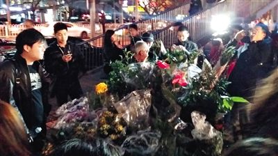 昨晚7時許，三里屯太古里西邊附近一過街天橋旁邊，聞訊而至的網(wǎng)友圍住了賣花老人，爭相買花。 網(wǎng)友“行者橙子”供圖