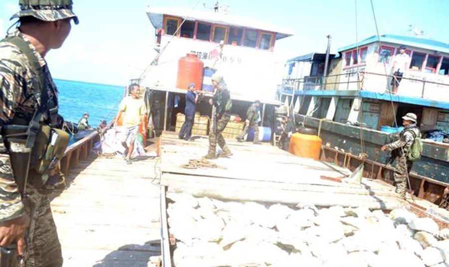 圖為菲律賓海軍持槍檢查中國漁民的照片。